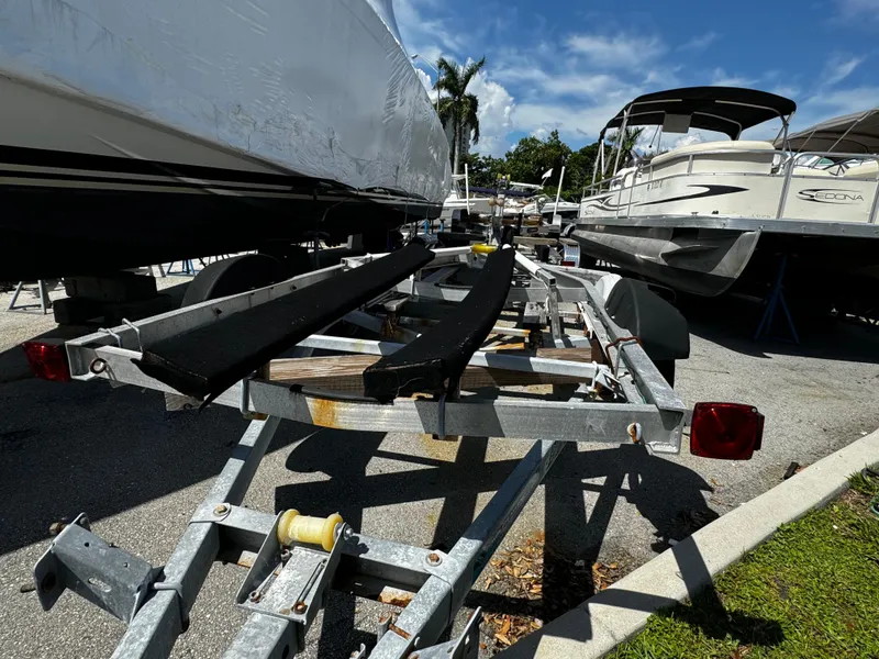 Slide: The Image of 2019 Continental Trailers Single Axel boat trailer parked between boats under a clear sky. - 7