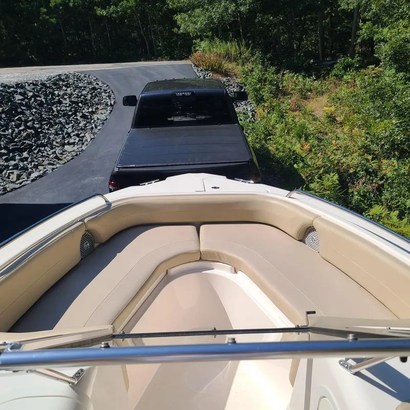 Slide: The Image of 2015 Pursuit DC 235 Dual Console boat parked near black truck on driveway. - 10