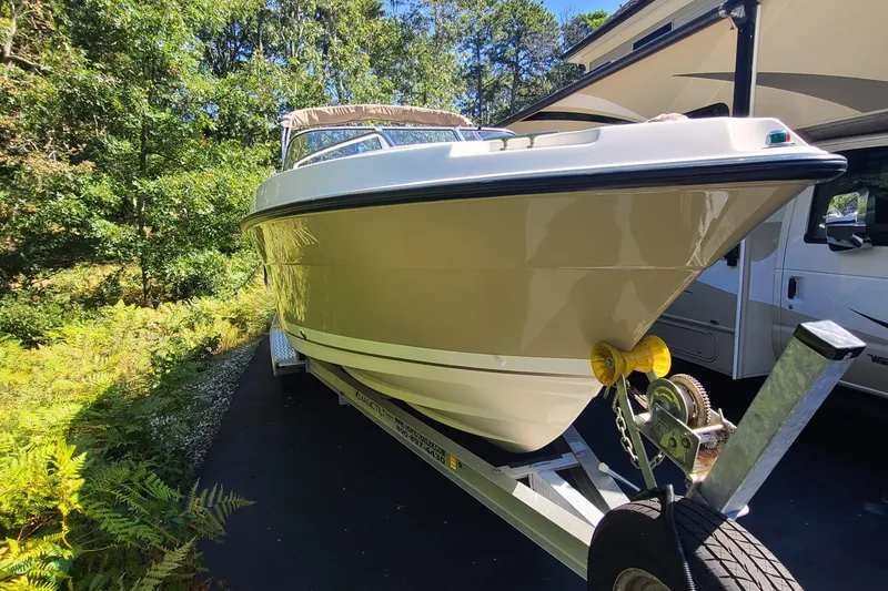 Slide: The Image of 2015 Pursuit DC 235 Dual Console boat on trailer, surrounded by greenery. - 22