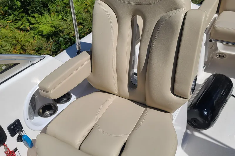 Slide: The Image of 2015 Pursuit DC 235 Dual Console boat seat with beige upholstery and armrest. - 29