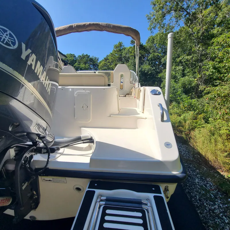 Slide: The Image of 2015 Pursuit DC 235 Dual Console boat with Yamaha engine, docked near lush greenery. - 4