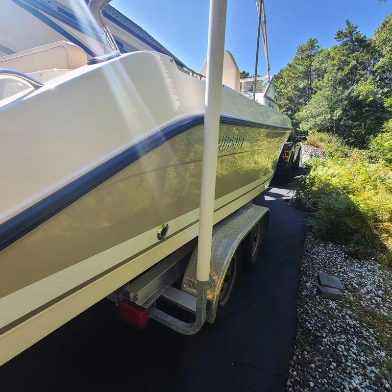 Slide: The Image of 2015 Pursuit DC 235 Dual Console boat on trailer, parked on a sunny driveway. - 5