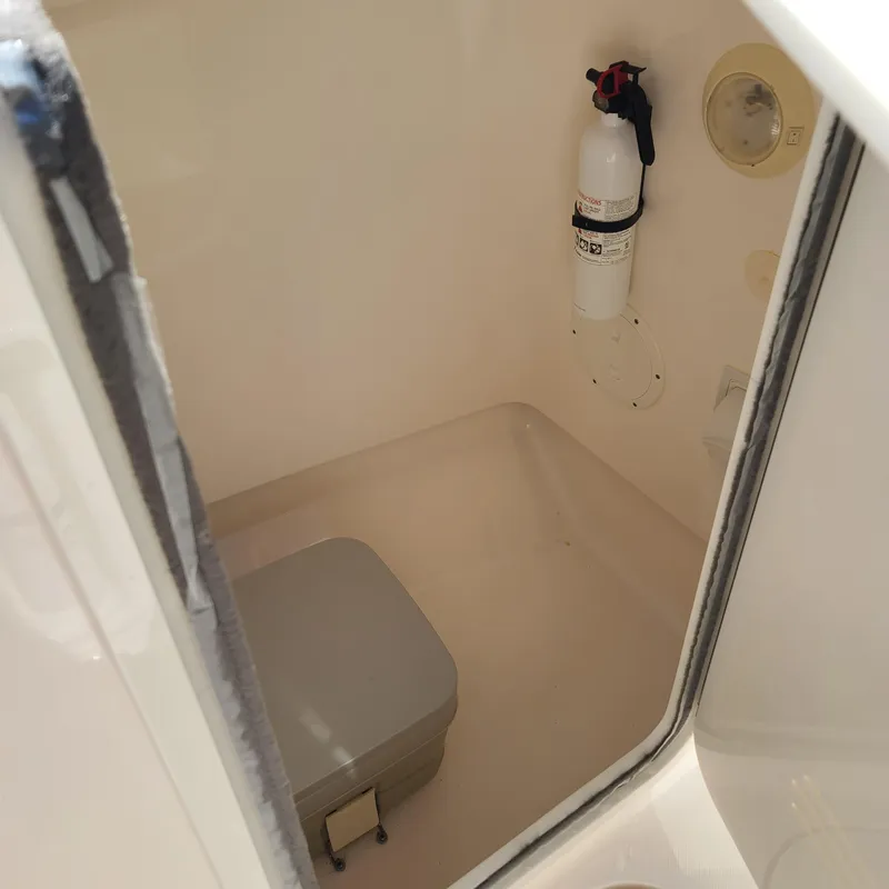 Slide: The Image of 2015 Pursuit DC 235 Dual Console boat interior with fire extinguisher and portable toilet. - 9