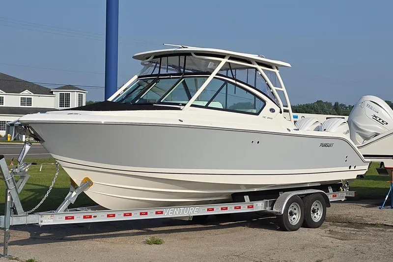 Slide: The Image of 2025 Pursuit DC 266 Dual Console boat on trailer, displayed outdoors. - 1
