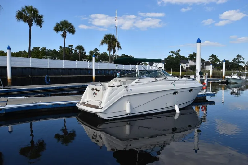 Slide: The Image of 1999 Rinker 270 Fiesta Vee boat docked in a serene marina setting. - 2