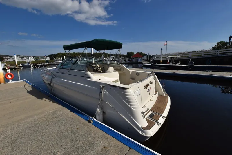Slide: The Image of 1999 Rinker 270 Fiesta Vee boat docked at marina under blue sky. - 4