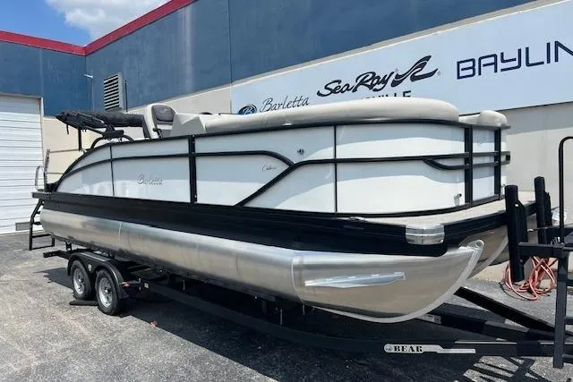 The Image of 2025 Barletta C22UC pontoon boat on trailer, parked outside dealership. - 0