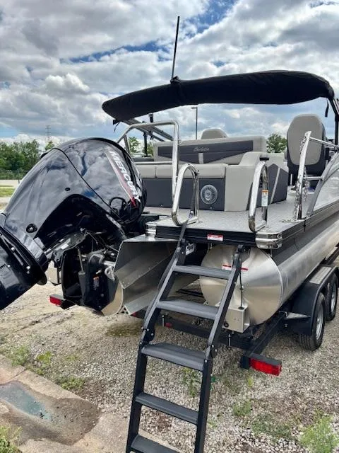 Slide: The Image of 2025 Barletta C22UC pontoon boat with outboard motor and ladder, parked on a trailer. - 5