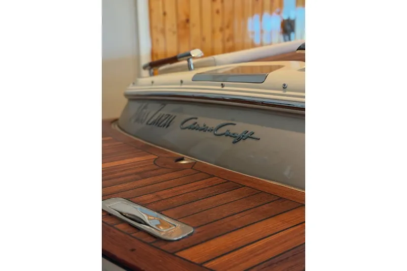 Slide: The Image of 2014 Chris-Craft Capri 21 boat in a marina lift, showcasing sleek design and wood accents. - 36
