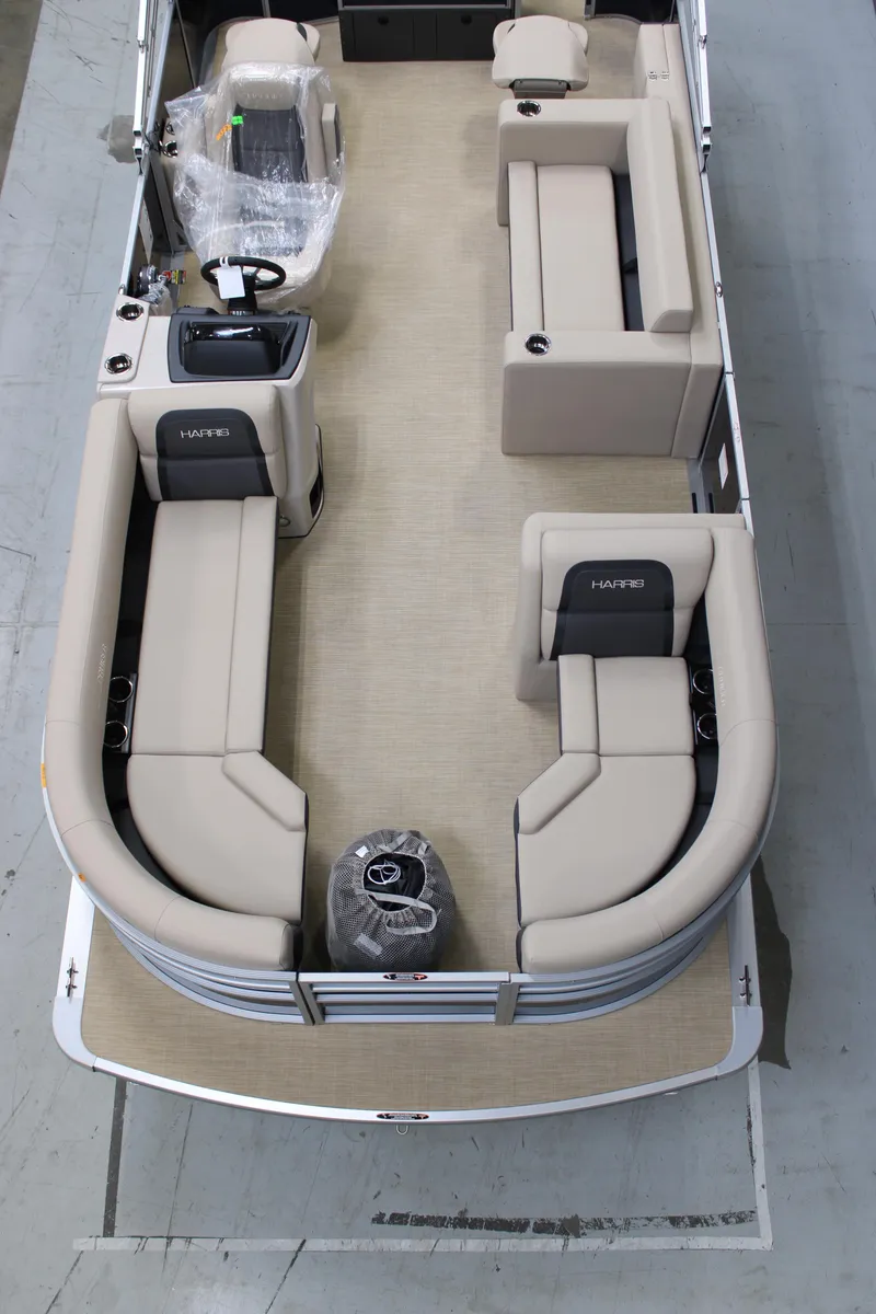 Slide: The Image of 2025 Harris Cruiser 210 FC pontoon boat interior with beige seating and steering console. - 2
