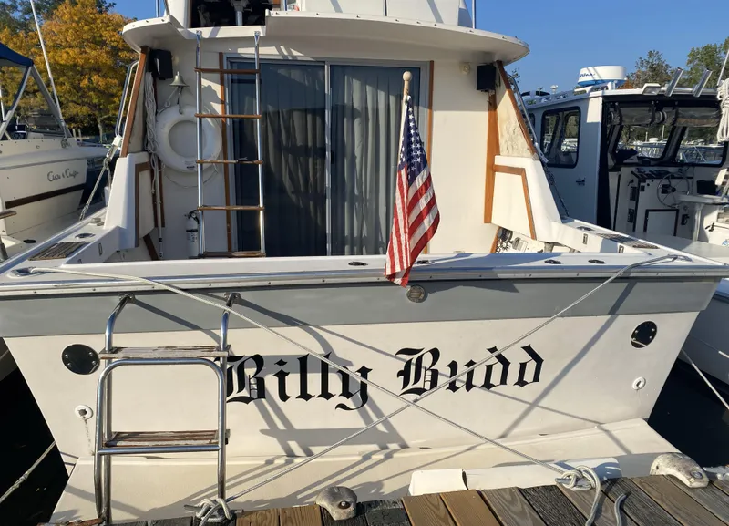 Slide: The Image of 1987 Silverton 34 Convertible boat with American flag, docked at marina. - 3