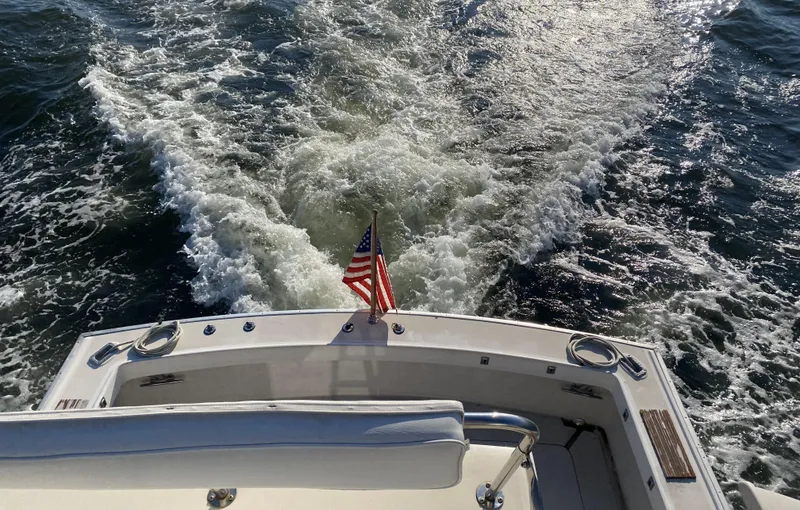 Slide: The Image of 1987 Silverton 34 Convertible boat cruising with American flag, leaving a wake in the water. - 4
