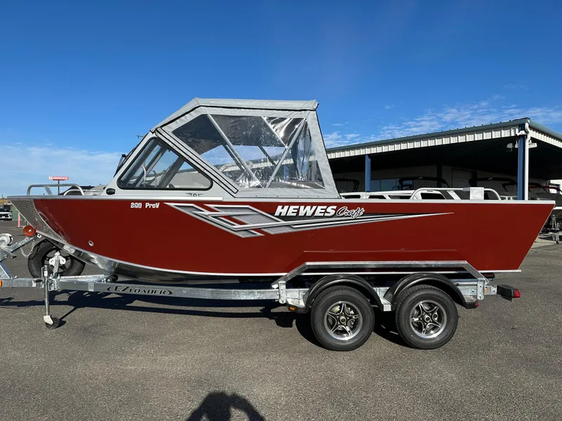 Slide: The Image of 2025 Hewescraft 200 ProV boat on trailer, red exterior, clear sky background. - 1