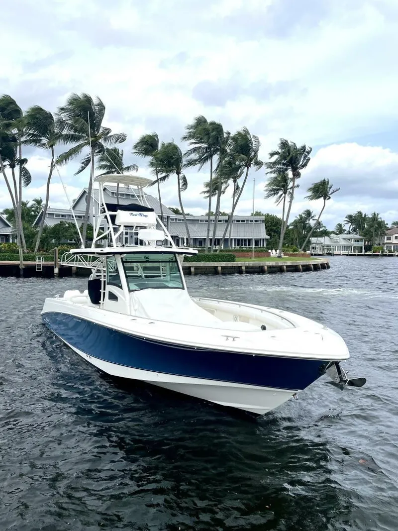 Slide: The Image of 2013 Boston Whaler 370 Outrage boat on water, palm trees in background. - 4