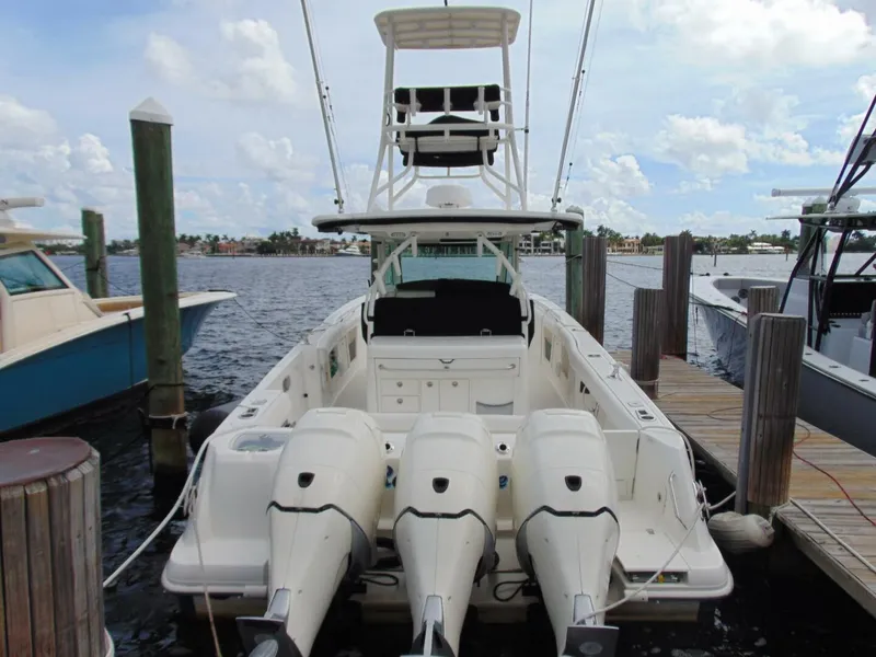 Slide: The Image of 2013 Boston Whaler 370 Outrage docked, featuring triple outboard engines. - 7