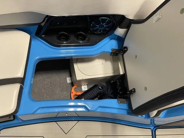 Slide: The Image of 2023 Yamaha Boats 255XD interior storage compartment with blue accents and cup holders. - 29