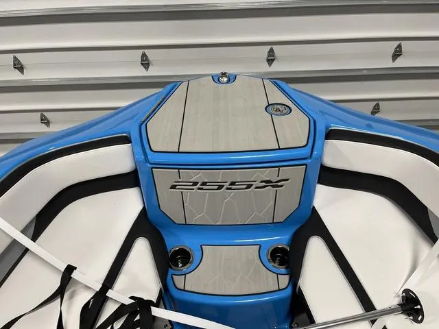 Slide: The Image of 2023 Yamaha Boats 255XD bow with blue and white seating, docked in a garage. - 30