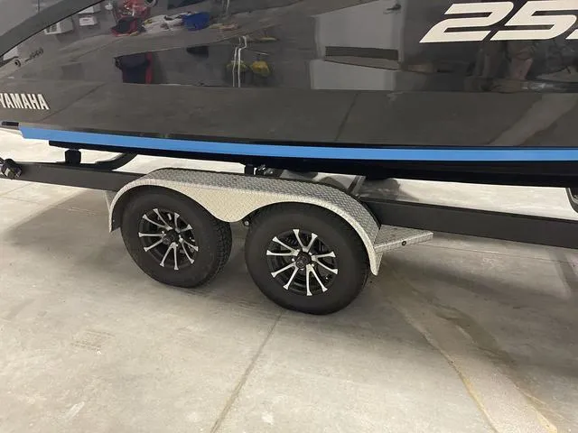 Slide: The Image of 2023 Yamaha Boats 255XD on trailer, showcasing sleek design and dual axle wheels. - 48