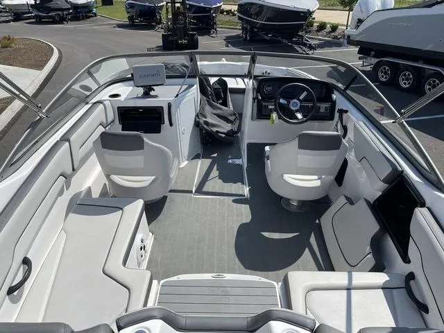 Slide: The Image of 2019 Yamaha Boats SX190 interior with seating and steering wheel, parked among other boats. - 10