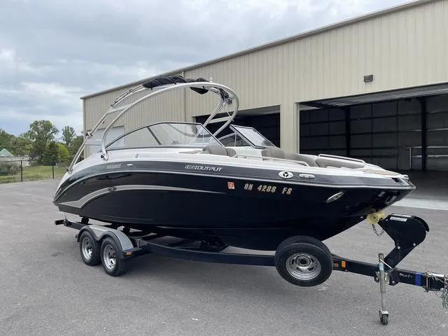 Slide: The Image of 2012 Yamaha Boats 242 Limited S on trailer, parked near a large garage. - 3