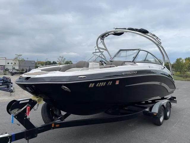 Slide: The Image of 2012 Yamaha Boats 242 Limited S on trailer, sleek black design, overcast sky. - 4