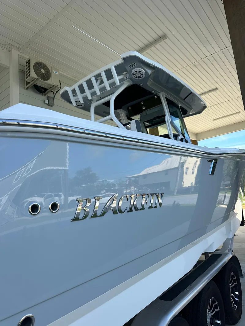 Slide: The Image of 2023 Blackfin 302CC boat under a covered area, showcasing sleek design and branding. - 10