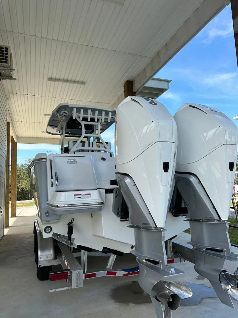 Slide: The Image of 2023 Blackfin 302CC boat with dual outboard engines on a trailer under a canopy. - 13