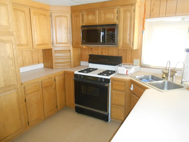 Slide: The Image of 1986 Hanson houseboat kitchen with wooden cabinets, stove, microwave, and dual sink. - 16