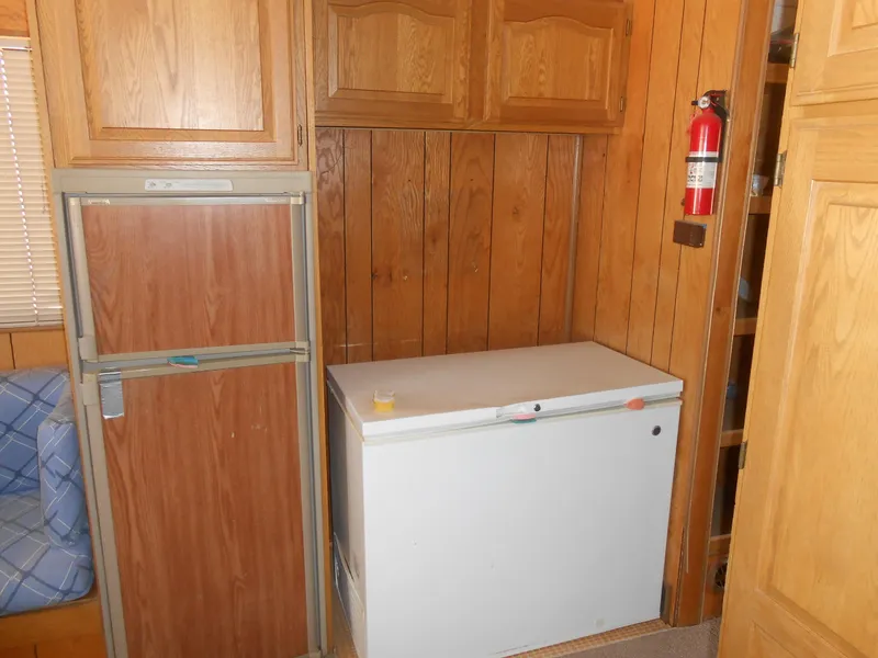 Slide: The Image of 1986 Hanson houseboat interior with wood paneling, fridge, freezer, and fire extinguisher. - 17
