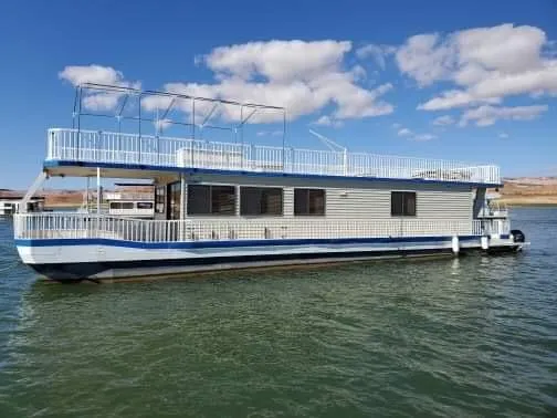 Slide: The Image of 1986 Hanson houseboat on a lake, featuring a two-level deck under a blue sky. - 2