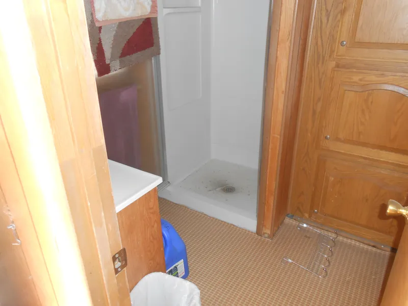 Slide: The Image of 1986 Hanson houseboat bathroom with shower, wooden cabinets, and carpeted floor. - 25