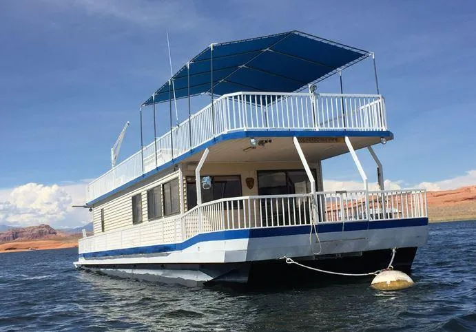 Slide: The Image of 1986 Hanson houseboat with blue canopy, floating on a calm lake under a clear sky. - 3