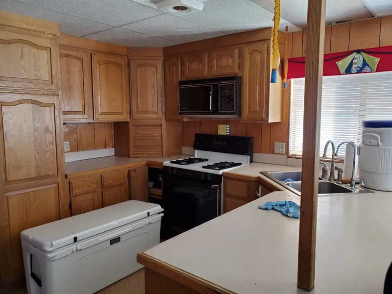 Slide: The Image of 1986 Hanson houseboat kitchen with wooden cabinets, stove, microwave, and sink. - 6