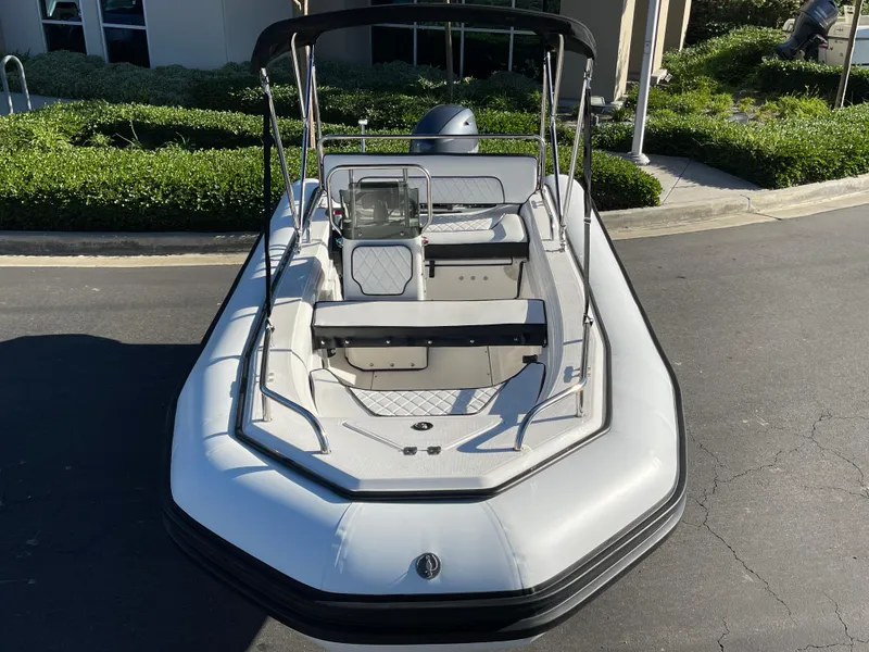 Slide: The Image of 1998 Rendova 14 boat with seating, parked on pavement, surrounded by greenery. - 15