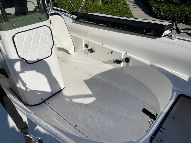 Slide: The Image of Interior of a 1998 Rendova 14 boat, featuring a clean, white deck and seating area. - 20