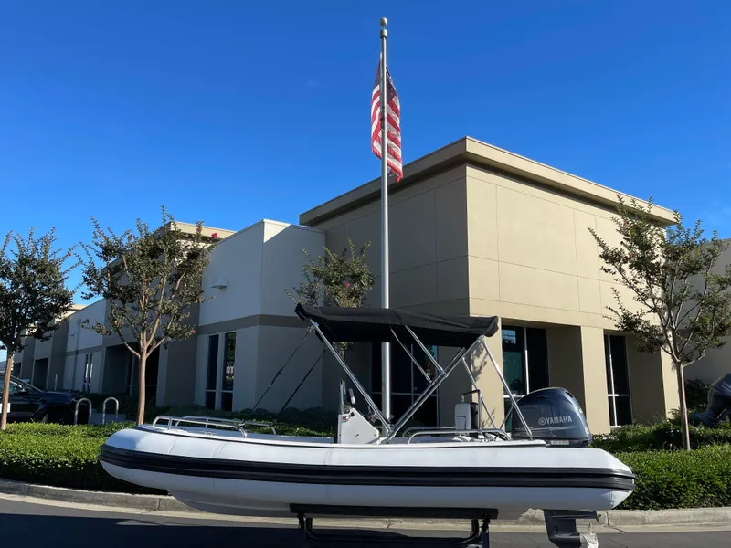 Slide: The Image of Rendova 14 inflatable boat, 1998 model, parked outside modern building with American flag. - 24