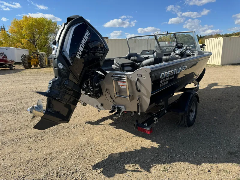 Slide: The Image of 2018 Crestliner 1850 Fish Hawk WT boat with Evinrude motor on gravel lot. - 2