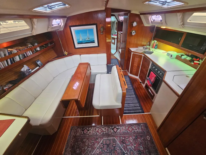 Slide: The Image of Interior of 1990 Catalina 42 sailboat with cozy seating, kitchen, and wooden finishes. - 14