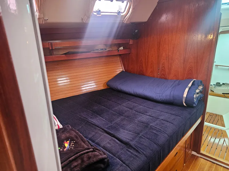 Slide: The Image of Cozy cabin interior of 1990 Catalina 42 sailboat with wooden paneling and blue bedding. - 16