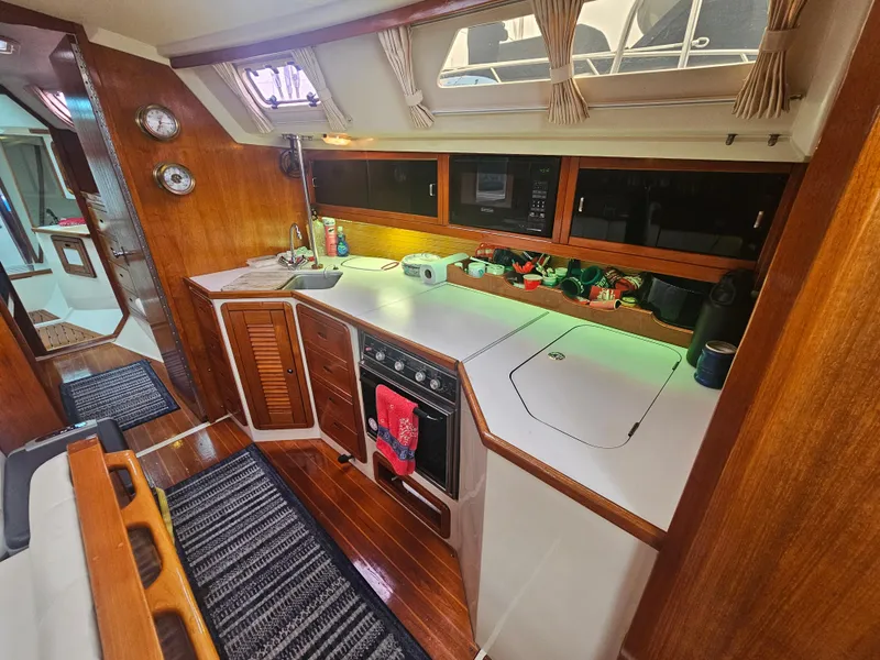 Slide: The Image of Interior of a 1990 Catalina 42 sailboat kitchen with wooden cabinetry and modern appliances. - 17
