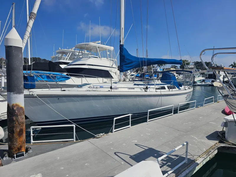 Slide: The Image of Catalina 42 sailboat from 1990 docked at a marina under a clear blue sky. - 2