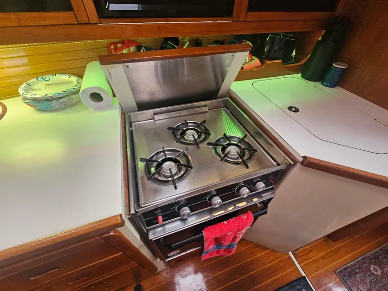 Slide: The Image of Three-burner stove in 1990 Catalina 42 yacht kitchen, with wooden cabinetry and countertop. - 23
