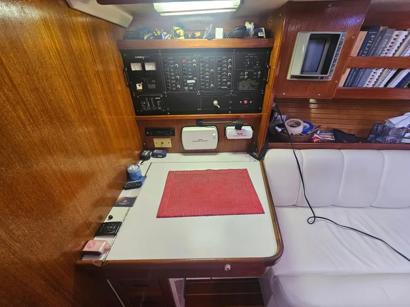 Slide: The Image of Navigation station inside a 1990 Catalina 42 sailboat with control panels and seating area. - 26