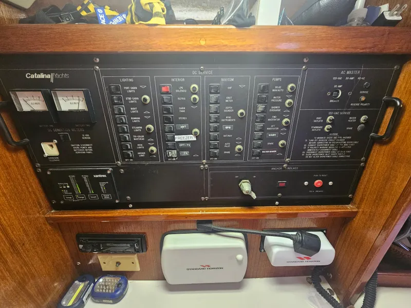 Slide: The Image of Control panel of a 1990 Catalina 42 sailboat, featuring various switches and gauges. - 28