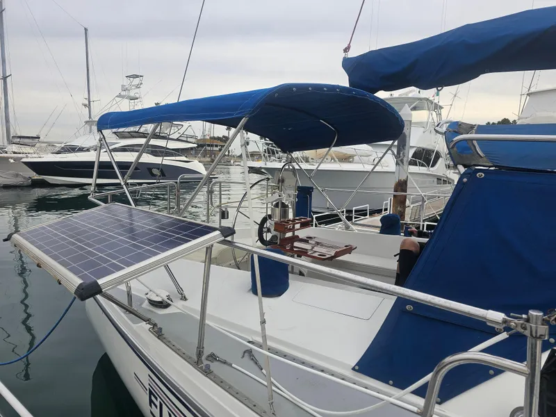 Slide: The Image of 1990 Catalina 42 sailboat with blue canopy and solar panel, docked in a marina. - 40