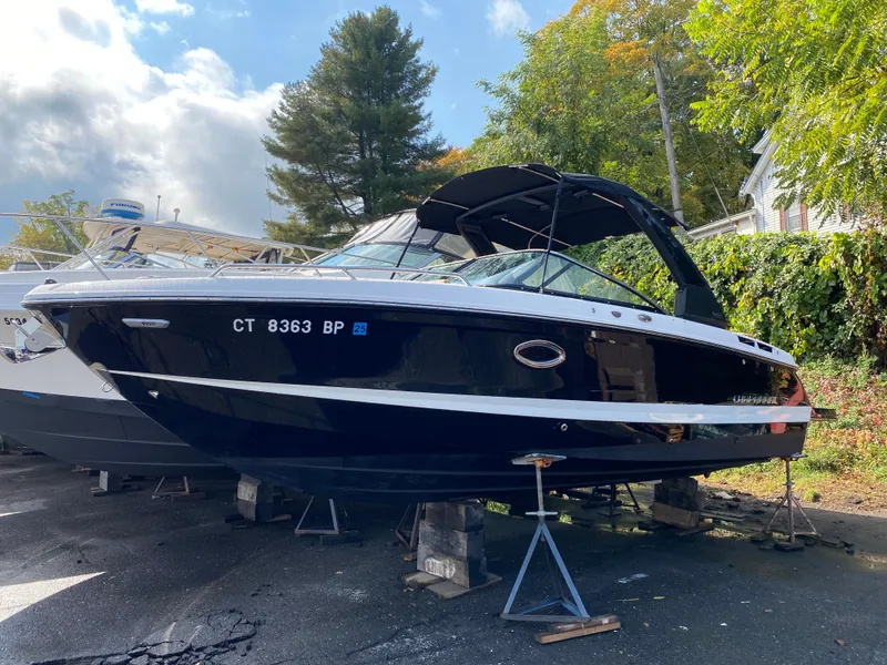 Slide: The Image of 2024 Chaparral 267 SSX boat on stands, outdoors, with trees in background. - 1