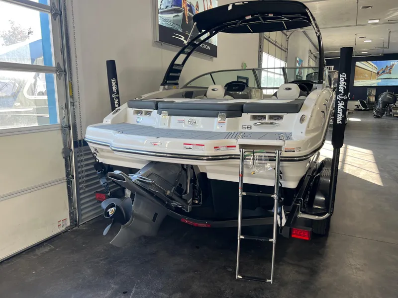 Slide: The Image of 2025 Chaparral 21 SSi boat in showroom, rear view with ladder and engine visible. - 17