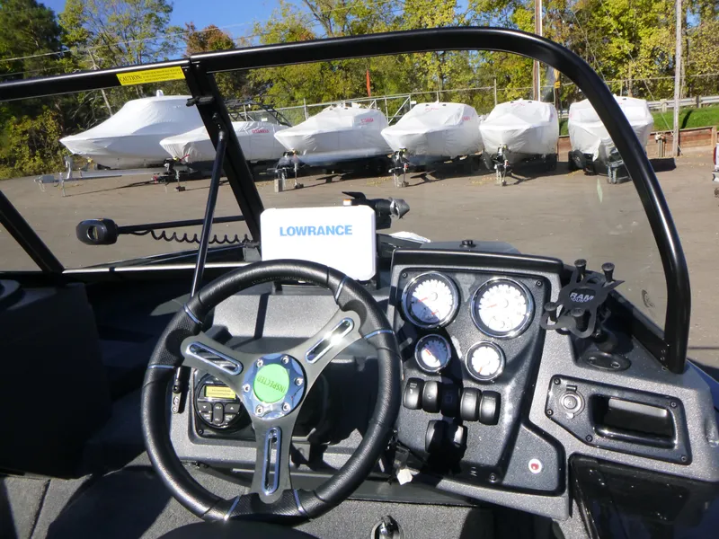Slide: The Image of 2025 Tracker Targa V-18 Combo boat dashboard with Lowrance system, parked near covered boats. - 25