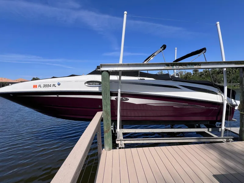 The Image of 2012 Sea Ray 280 Sundeck boat docked on a lift, clear blue sky background. - 0