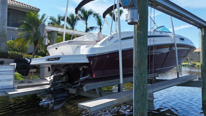 Slide: The Image of 2012 Sea Ray 280 Sundeck boat on lift, docked near waterfront homes and palm trees. - 12